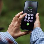 Young adult caucasian man attempting emergency call on smartphone in forest