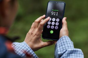 Young adult caucasian man attempting emergency call on smartphone in forest