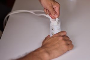 Ręce ostrożnie podłączają wtyczkę do listwy zasilającej dla wygodnego ładowania