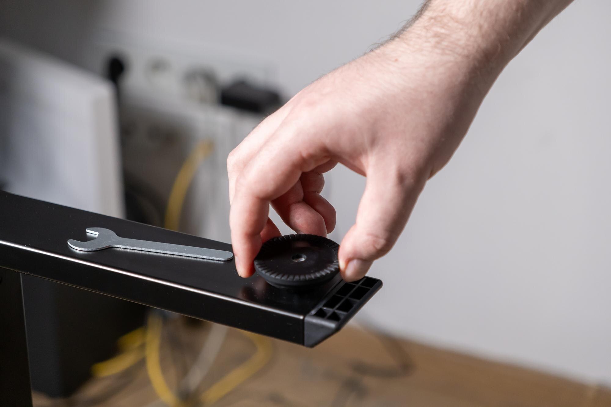 Worker39s hand carefully installs a durable black adjustable plastic foot onto a sturdy new metal furniture leg demonstrating practical home assembly maintenance and DIY repair skills