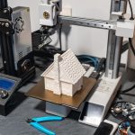 Plastic 3d printer working on printing a small house to scale for board games