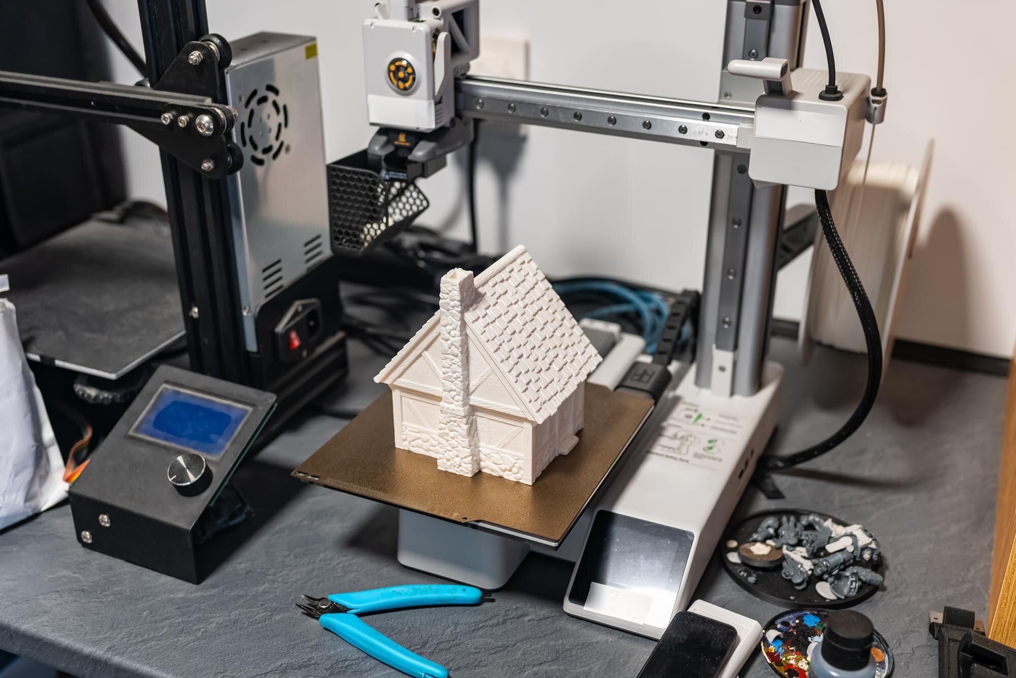 Plastic 3d printer working on printing a small house to scale for board games