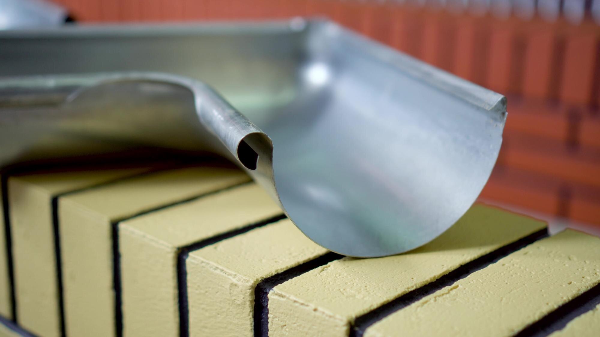 metal and plastic roof fastening elements gutter holders hooks and downpipes factory production industrial manufacturing process roofing components construction materials closeup metalworking