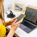 Zbliżenie Businesswoman z żółtą koszulą przy użyciu telefonu z pracy w domu
