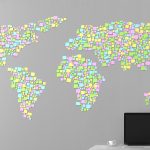 Mapa świata z naklejonych na ścianie naklejek obok stojącego laptopa