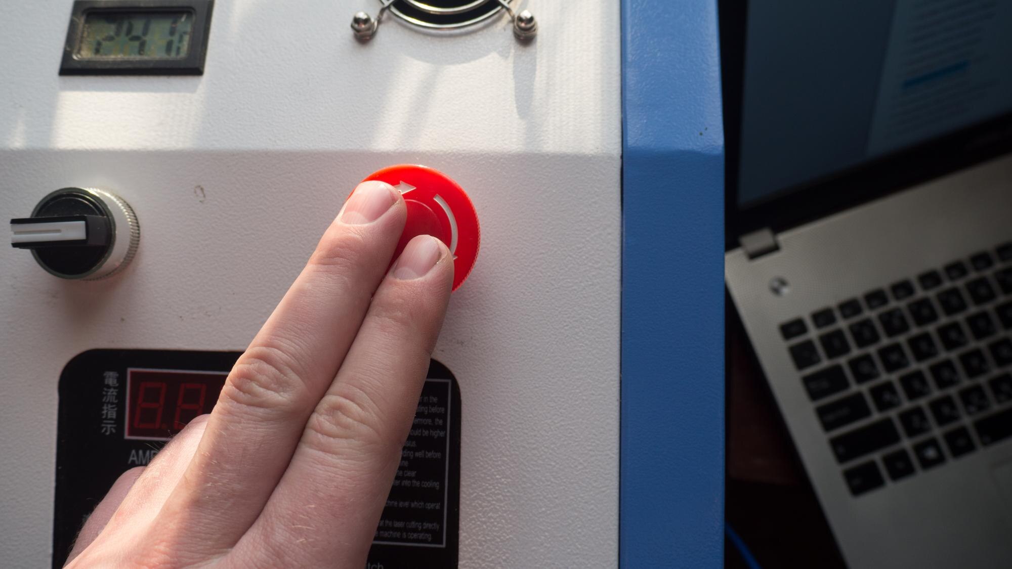 Ręka naciska czerwony przycisk na maszynie