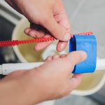 Ręka naprawia spłuczkę toaletową w domu