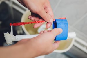 Ręka naprawia spłuczkę toaletową w domu