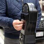 Mężczyzna płaci monetami za parkowanie na nowej ulicy swoim samochodem