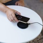 Ładowanie baterii telefonu komórkowego za pomocą bezprzewodowego urządzenia ładującego na stole Ładowanie smartfona na podkładce ładującej Telefon komórkowy w pobliżu ładowarki bezprzewodowej Koncepcja nowoczesnej technologii stylu życia