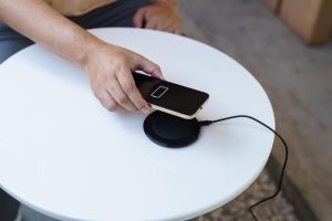 Ładowanie baterii telefonu komórkowego za pomocą bezprzewodowego urządzenia ładującego na stole Ładowanie smartfona na podkładce ładującej Telefon komórkowy w pobliżu ładowarki bezprzewodowej Koncepcja nowoczesnej technologii stylu życia