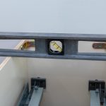 Podczas instalacji nowego zestawu szafek kuchennych pracownik wisi poziomo, aby upewnić się, że szafki są wypoziomowane