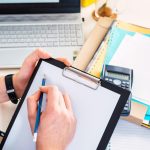 Zbliżenie męskiej ręki piszącej raport w schowku