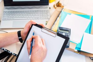 Zbliżenie męskiej ręki piszącej raport w schowku