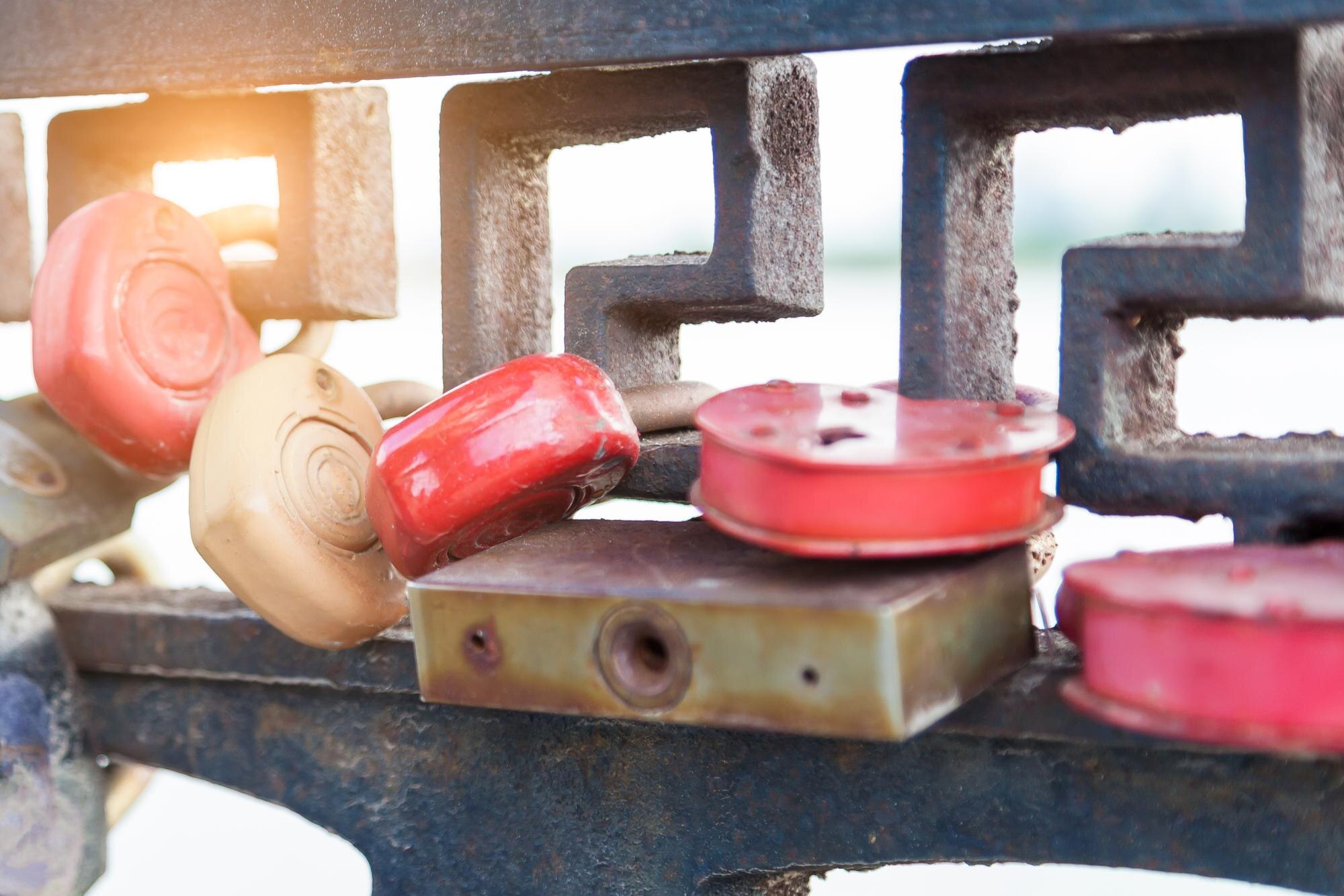 Zamki serc o różnych kolorach i kształtach wiszące w rzędach jeden na drugim na metalowym płocie na znak wiecznej miłości, które zostały zamknięte podczas ślubu na skarpie