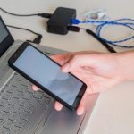 Męskie ręki sprawdza telefon komórkowego obok laptopa na biurku Selekcyjna ostrość