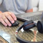 Mężczyzna pracuje na laptopie w domu Słuchawki leżą na stole w pobliżu