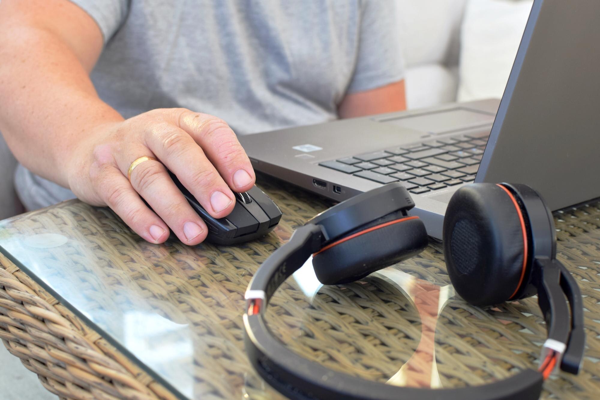 Mężczyzna pracuje na laptopie w domu Słuchawki leżą na stole w pobliżu