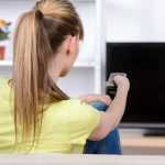 Piękna kobieta ogląda TV obsiadanie na leżance w domu.