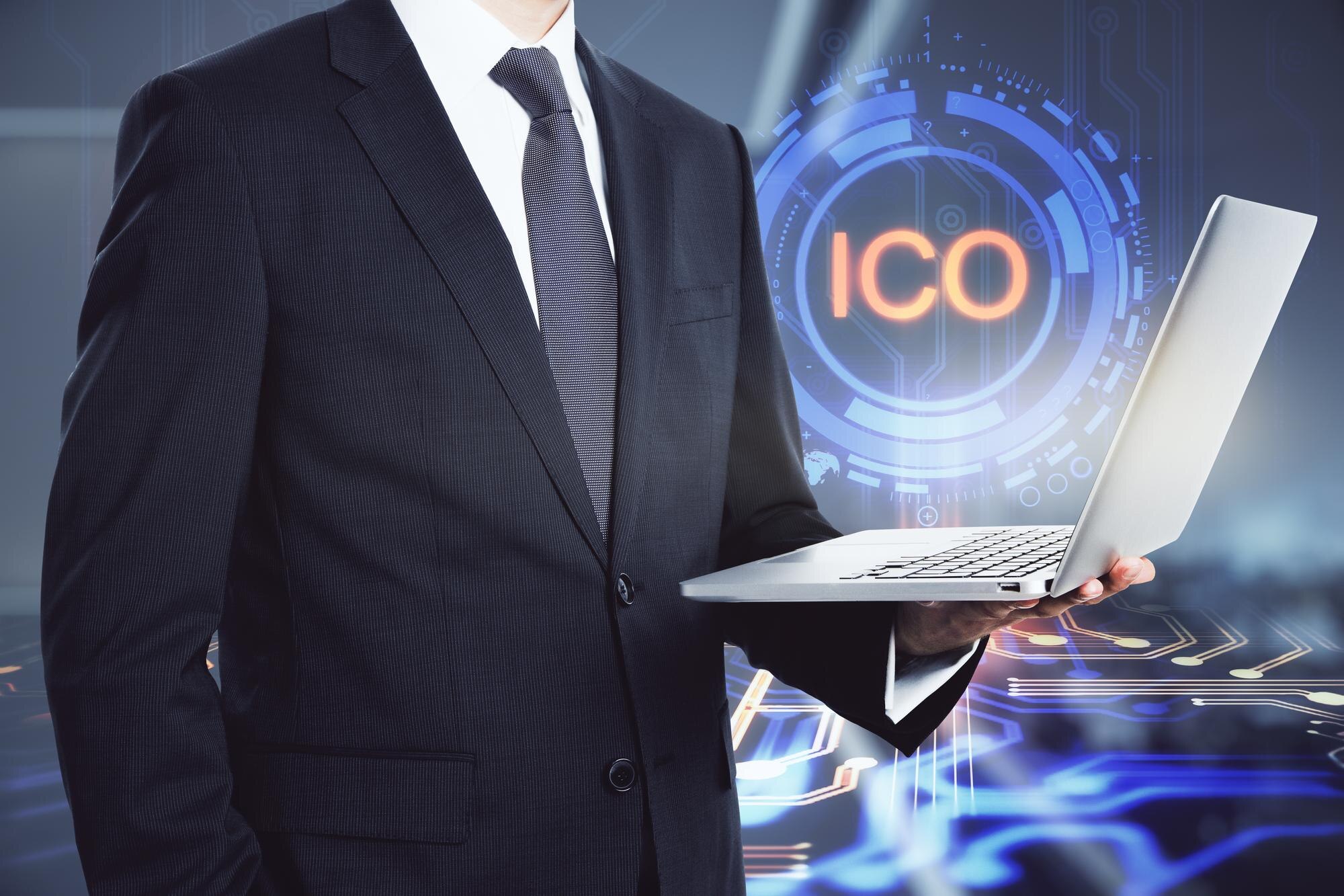 Biznesmen z laptopem stojącym na tle hologramu ICO uruchomienie i koncepcja decentralizacji