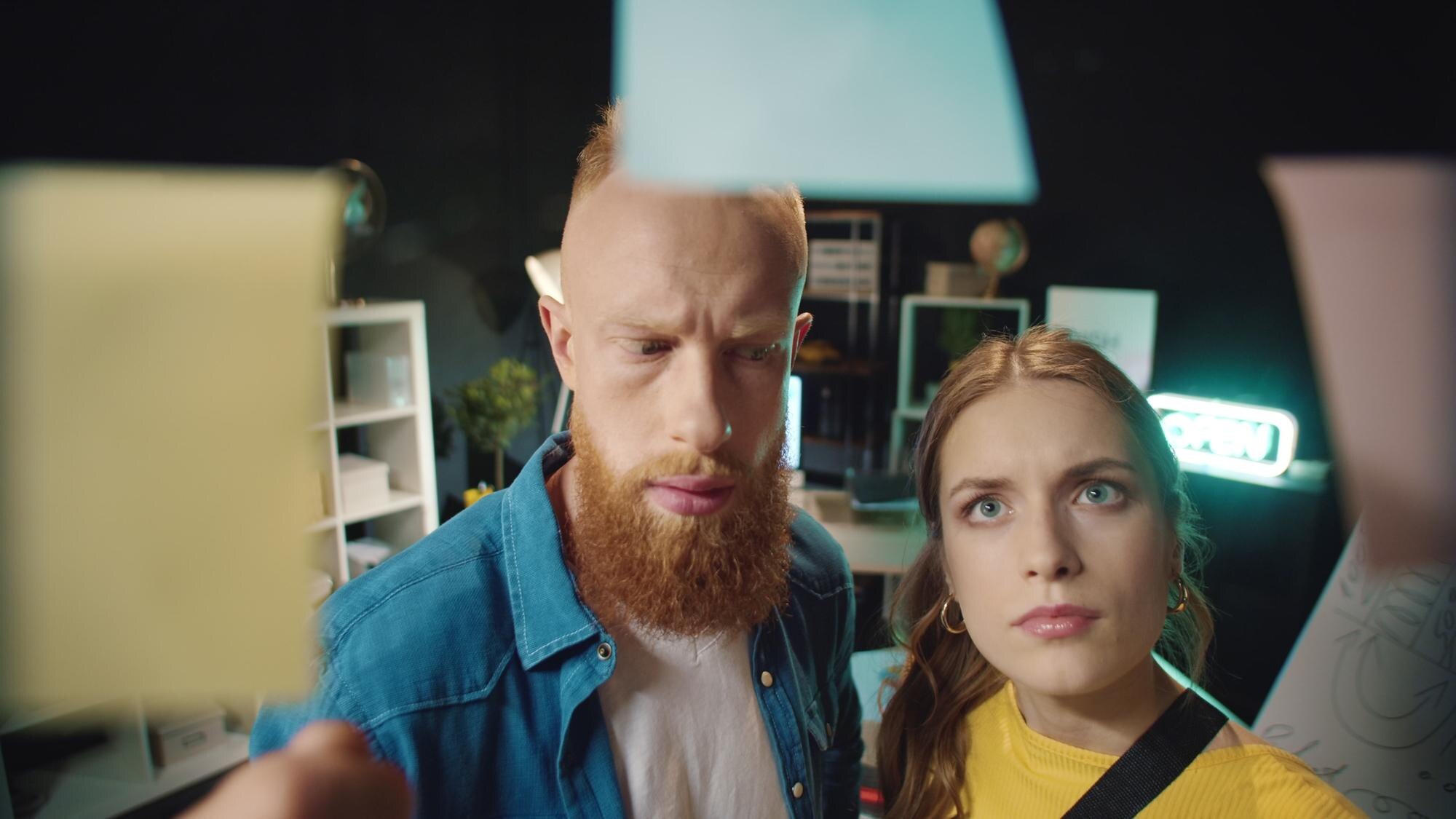 Zaskoczony hipster mężczyzna i kobieta znajdują dobry pomysł na przezroczystej ścianie w biurze