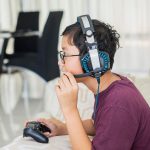 Chłopiec w wieku przed nastoletnim nosi słuchawki do gier wideo