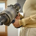 Sprzątanie domu koncepcja prac domowych Tysiącletnia Azjatka odkurzająca i czyszcząca kurz na kanapie w salonie