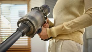 Sprzątanie domu koncepcja prac domowych Tysiącletnia Azjatka odkurzająca i czyszcząca kurz na kanapie w salonie