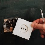 Mężczyzna elektryk usuwa stare gniazdko elektryczne