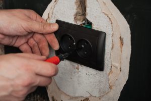 Wymiana i instalacja nowego gniazdka elektrycznego. Ręce z śrubokrętem mężczyzna elektryk