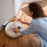 Kobieta w domu z automatycznym bezprzewodowym odkurzaczem