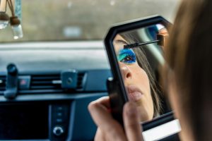 Lustrzane odbicie dziewczyny nakładającej makijaż w samochodzie Kobieta robiąca makijaż w samochodzie