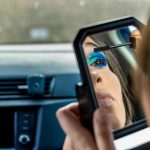 Lustrzane odbicie dziewczyny nakładającej makijaż w samochodzie Kobieta robiąca makijaż w samochodzie