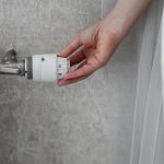 Kobieta regulująca temperaturę w celu oszczędzania grzejnika i zachowania ciepła w pomieszczeniu