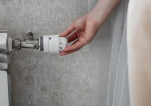 Kobieta regulująca temperaturę w celu oszczędzania grzejnika i zachowania ciepła w pomieszczeniu