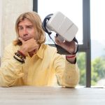 młody dorosły mężczyzna rasy kaukaskiej z szeroko otwartymi ustami i oczami i ręką na podbródku koncepcja wirtualnych okularów