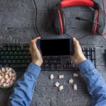 Urządzenie mobilne w rękach dziecka na tle biurka z zapleczem komputerowym