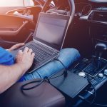 Mechanik z laptopem robiący diagnostykę samochodu w serwisie samochodowym