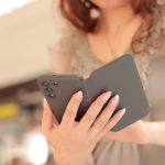 Gadget Girl z telefonem w dłoniach Damskie dłonie ze smartfonem w eleganckim etui z bliska