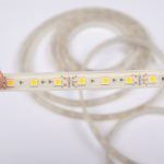 Trzymaj w ręku taśmę LED na białym tle, z bliska.