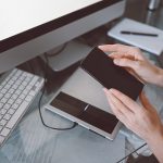 Kobieta ręce za pomocą inteligentnego telefonu w wewnętrznym miejscu pracy, niezależna kobieta biznesu za pomocą telefonu komórkowego na biurku, pracując w domu za pomocą inteligentnego telefonu i notebooka. Kwarantanna zdalnego pracownika