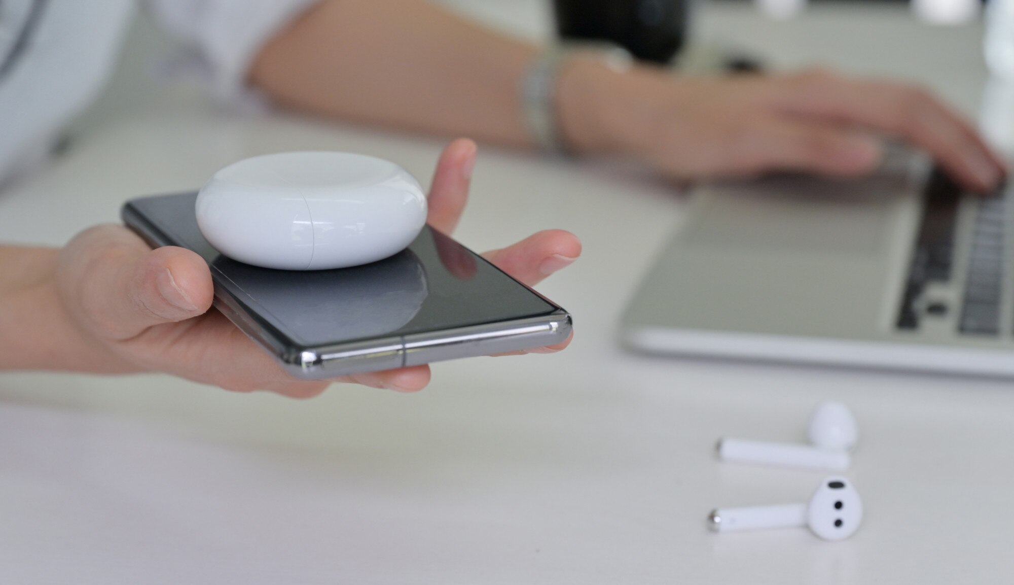 Młode kobiety zakładają słuchawki na smartfona, aby dzielić bezprzewodową ładowarkę.