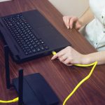 Kobieta podłącza kabel internetowy do złącza na laptopie