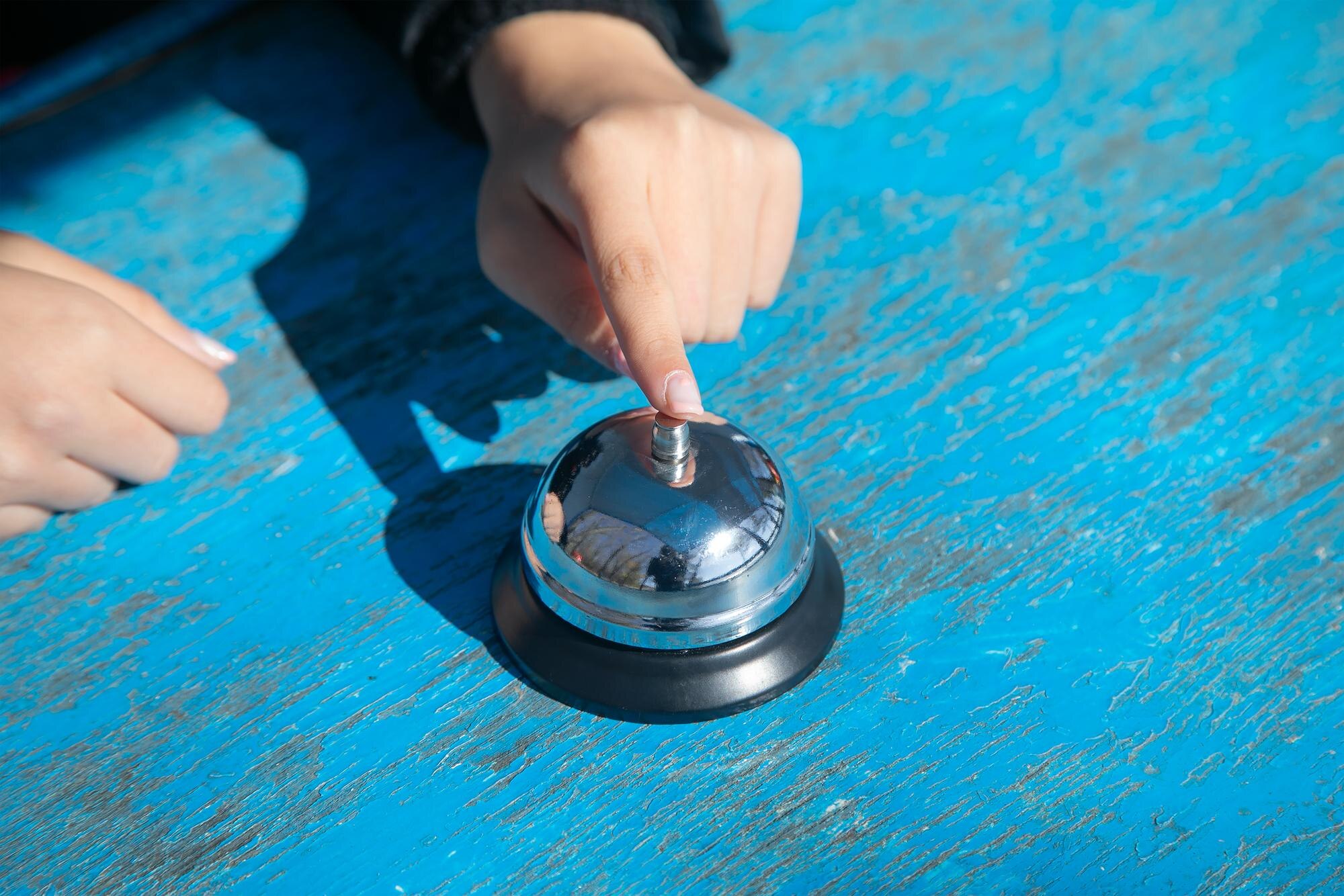 Kobieta dzwoni do dzwonka na stole