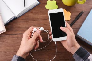 Koncepcja audiobooka Młody mężczyzna używający smartfona i słuchawek