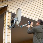 Naprawa anteny satelitarnej TV Właściciel domu zaciska zakrętki łączące