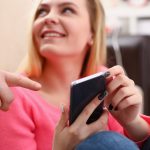 Młoda ładna blond womansit na kanapie trzymaj smartfon w rękach