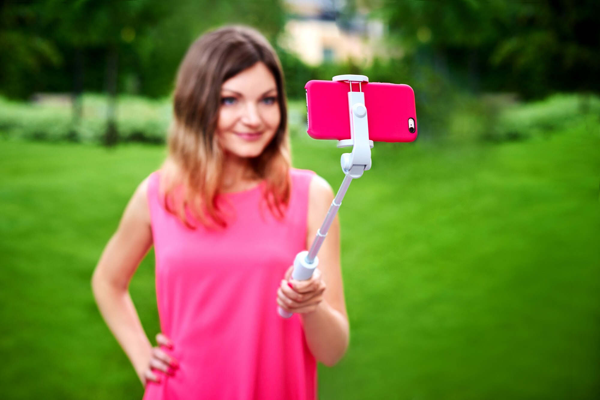 Uśmiechnięta kobieta bierze selfie na telefonie komórkowym z kijem outdoors