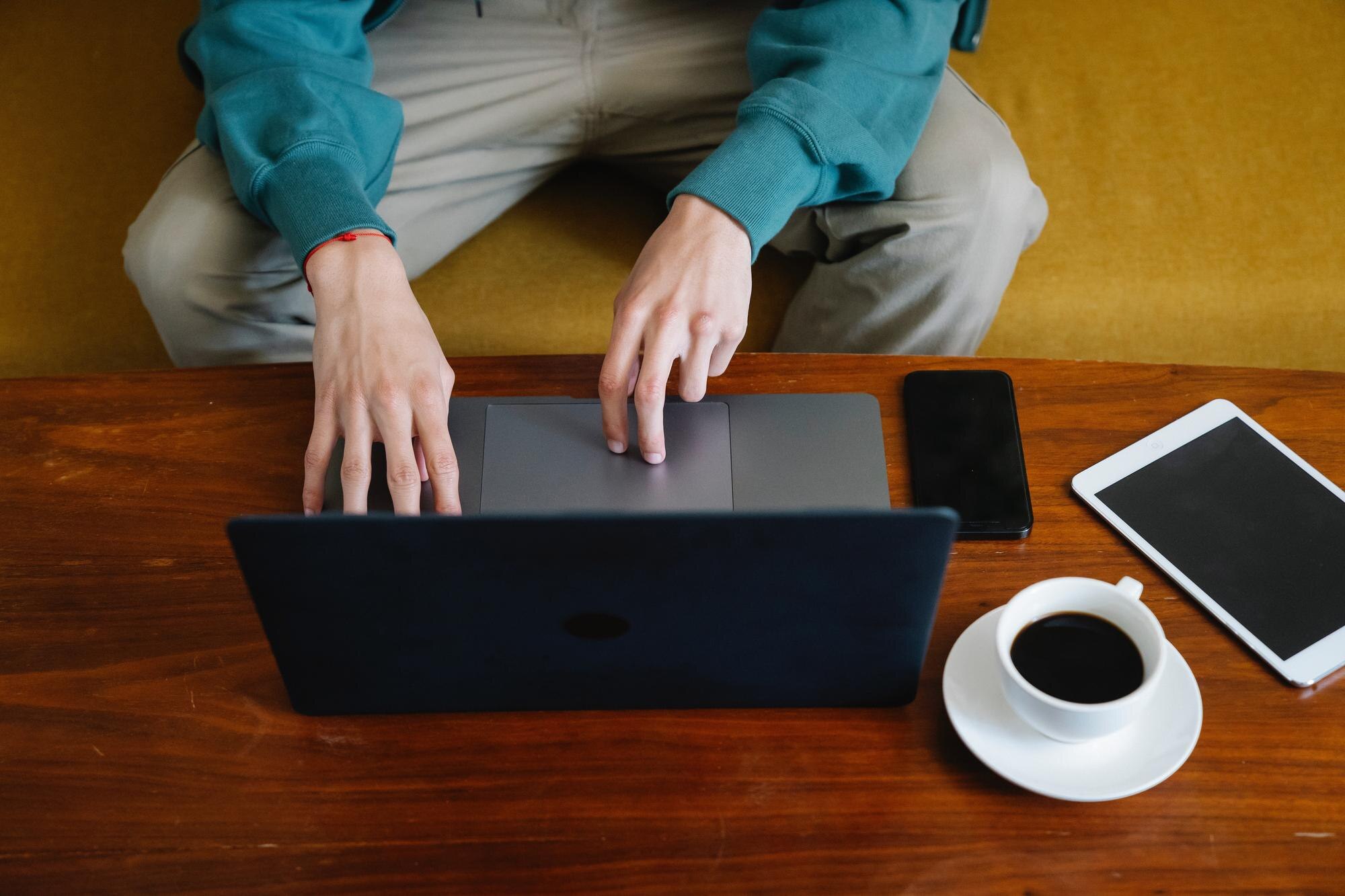 Uśmiechnięty indyjski biznesmen pracujący na laptopie w nowoczesnym biurze