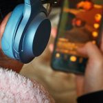 Tylny widok nastolatka na suficie za pomocą telefonu komórkowego z słuchawkami